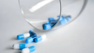 Modro-bílé tobolky vysypané ze skleničky na bílý podklad